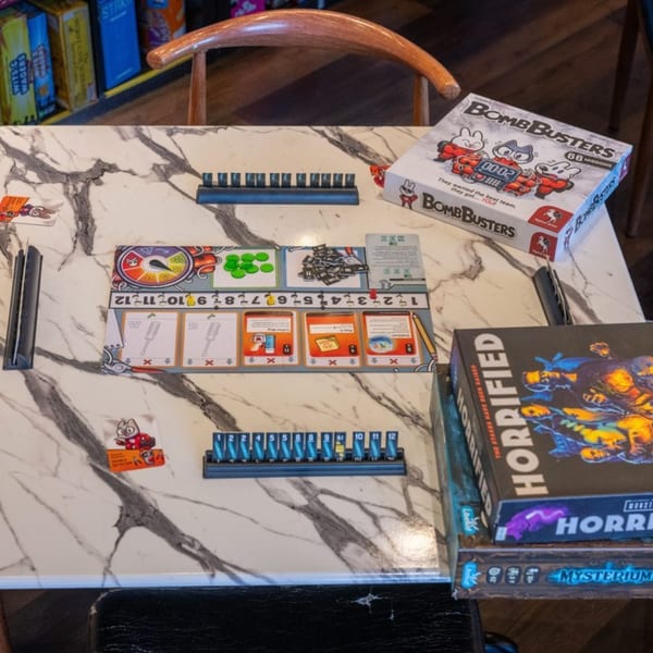 A marble table at The Board and Brew cafe with Bomb Busters and Horrified board games set up.